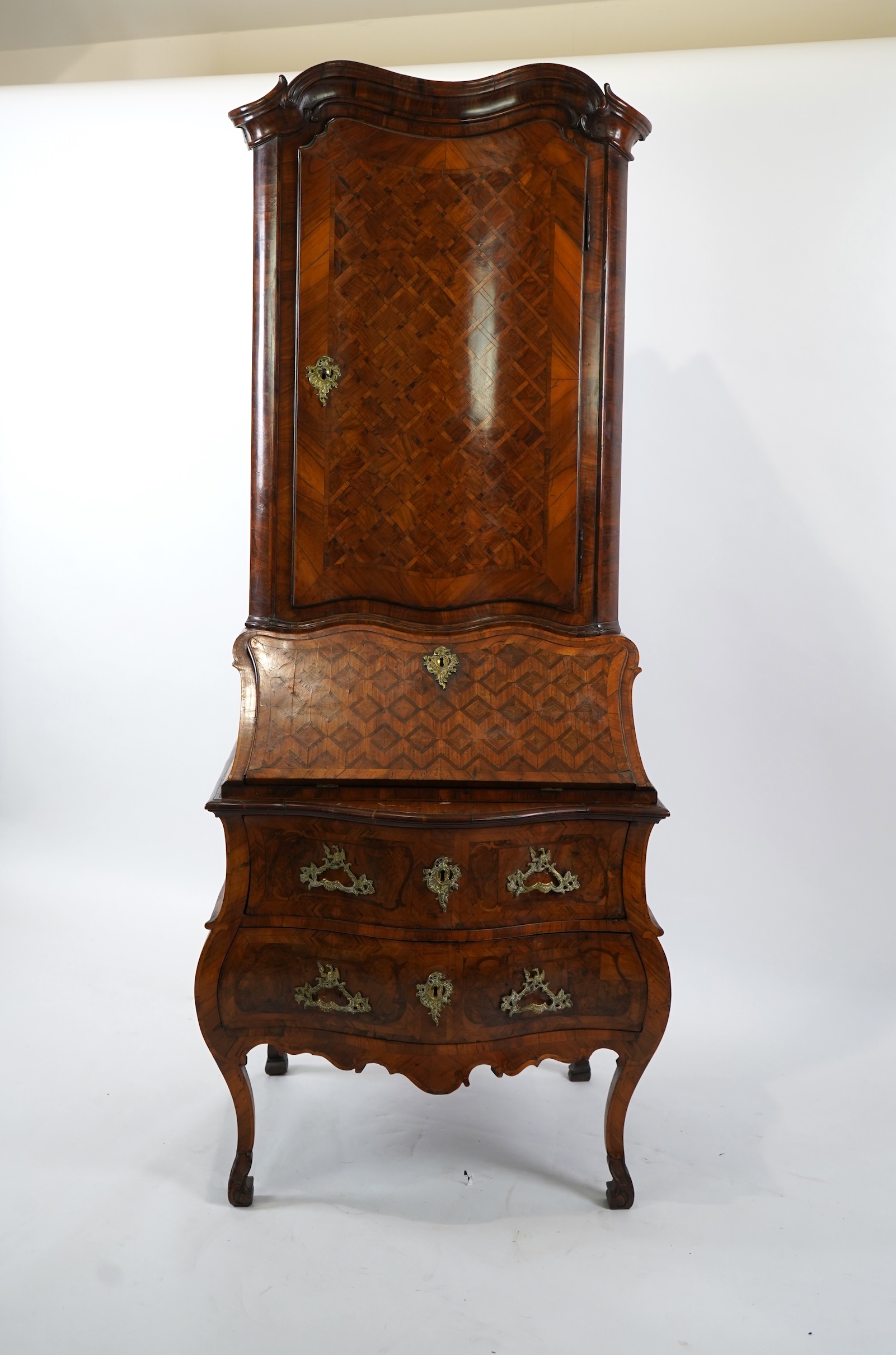 A mid 18th century North Italian or Maltese walnut and olive wood gilt metal mounted serpentine bureau cabinet